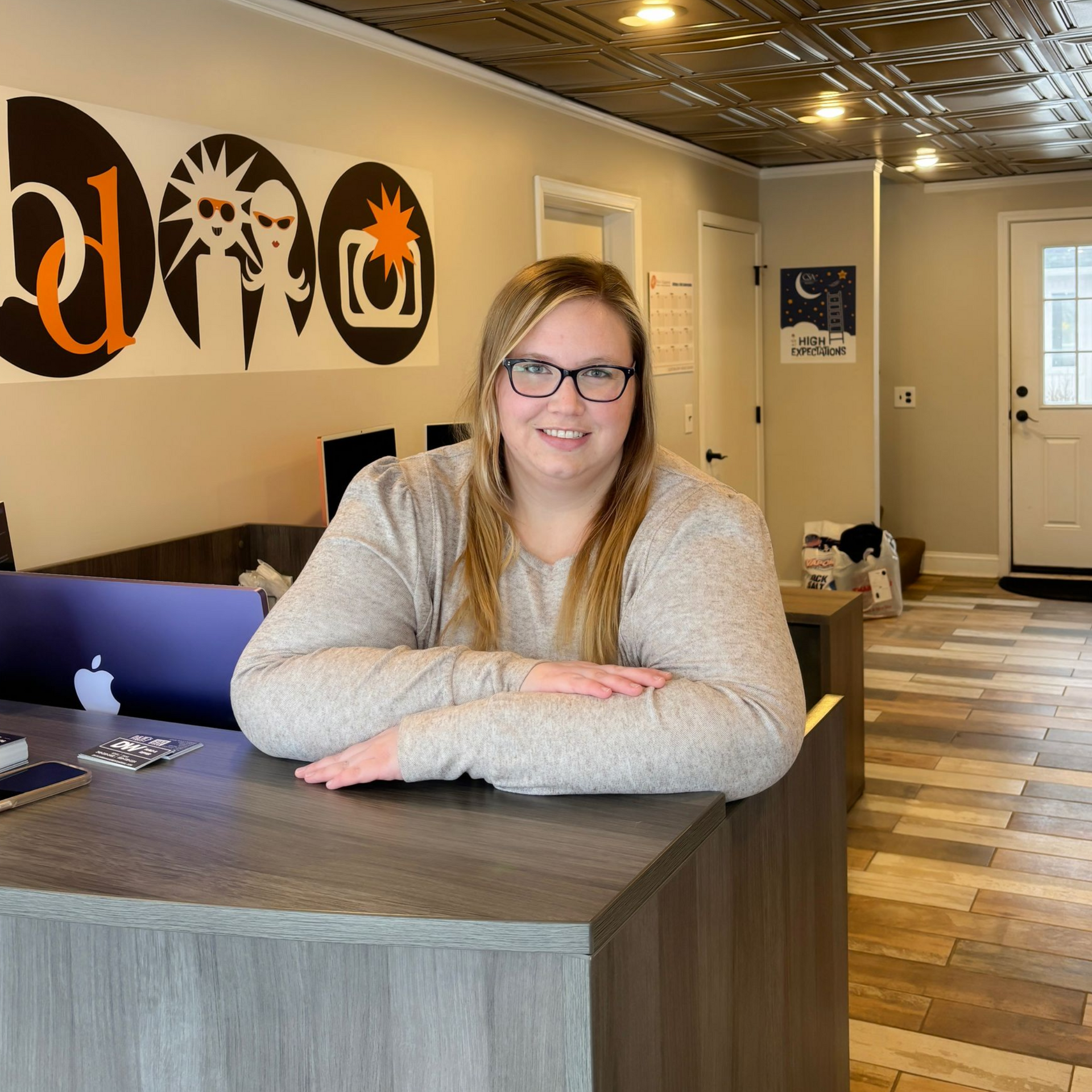 Smiling woman leaning on a reception desk in a bright office lobby