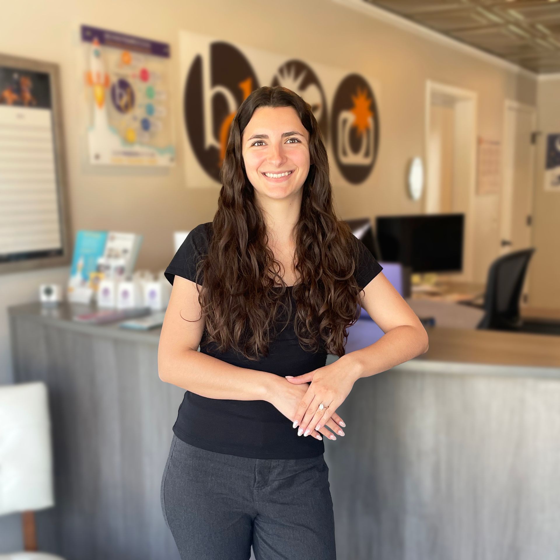 Woman smiling in a lobby with wood floors, wall art, and a reception desk.