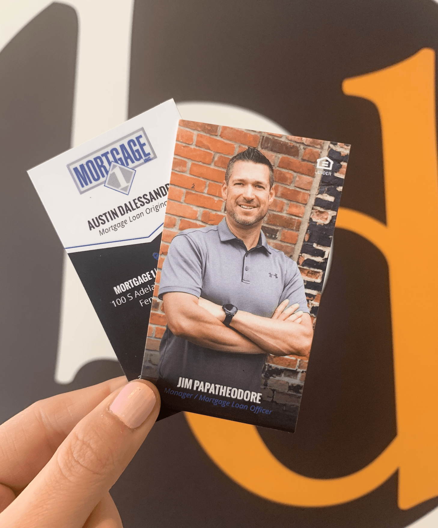 A person is holding a business card for mortgage with a picture of a man on it