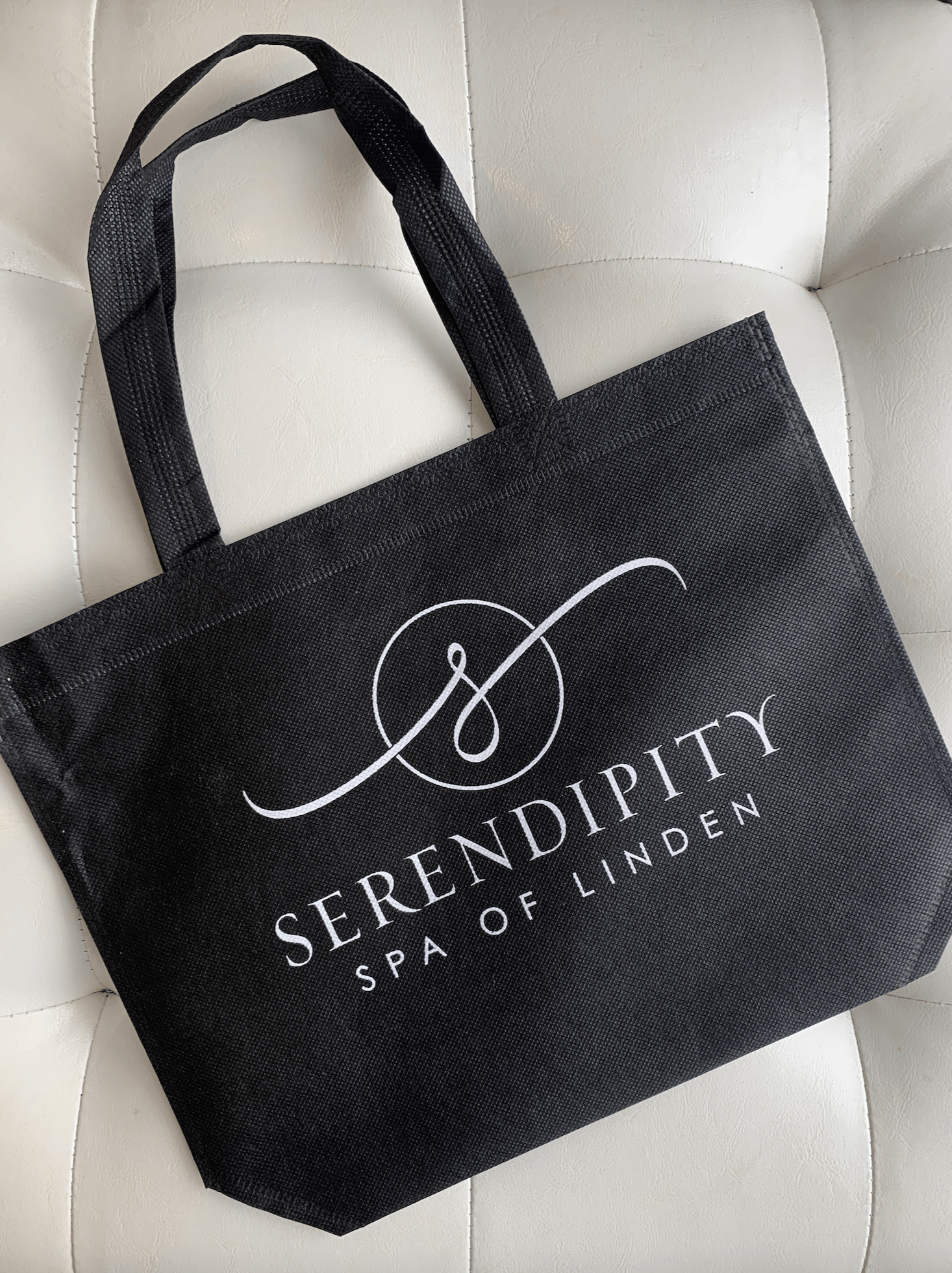 A black tote bag with the words serendipity spa of linden on it