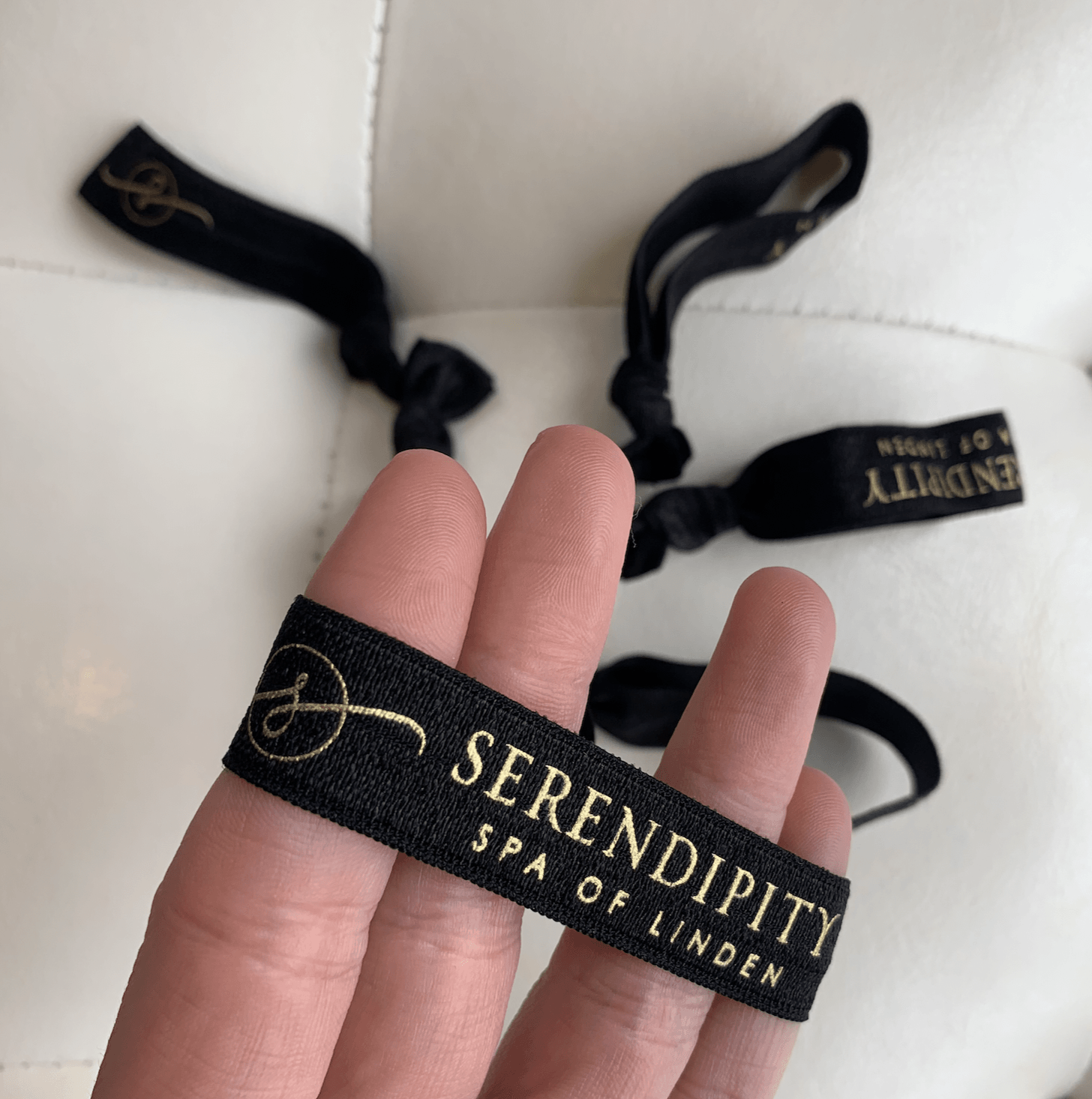 A person is holding a bracelet that says serendipity spa of linden