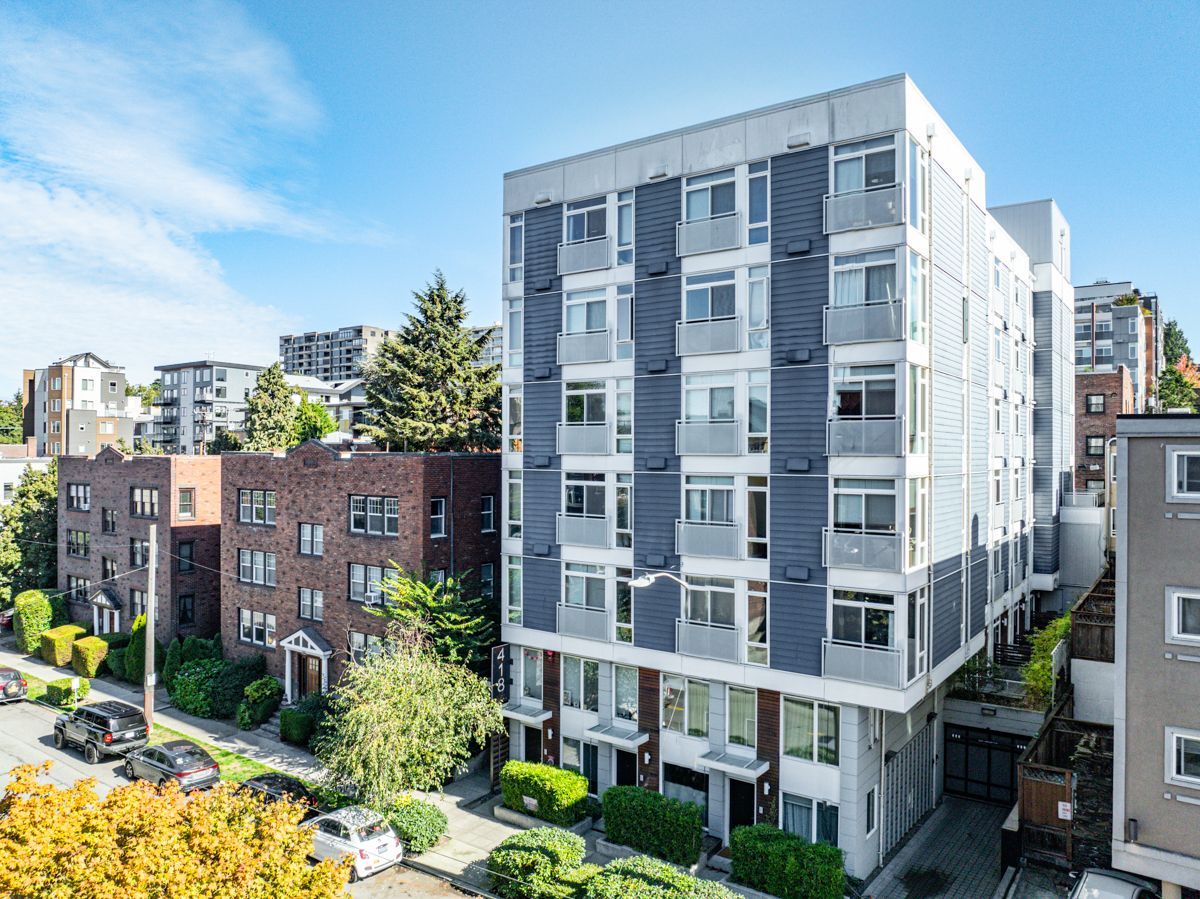 Modern apartment buildings with balconies along a leafy residential street