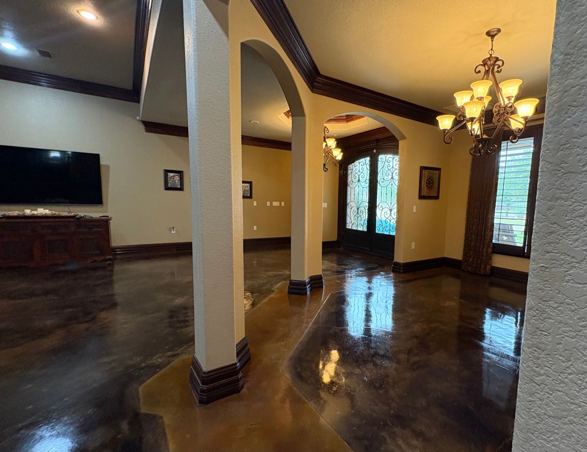 Interior view of a home with columns, arched doorways, and decorative flooring.