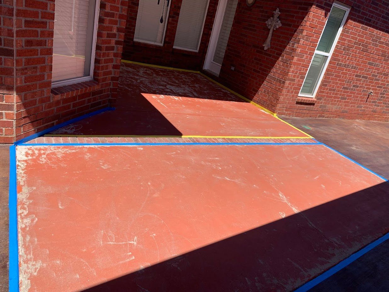 Brick building with red concrete patio outlined in blue and yellow tape.