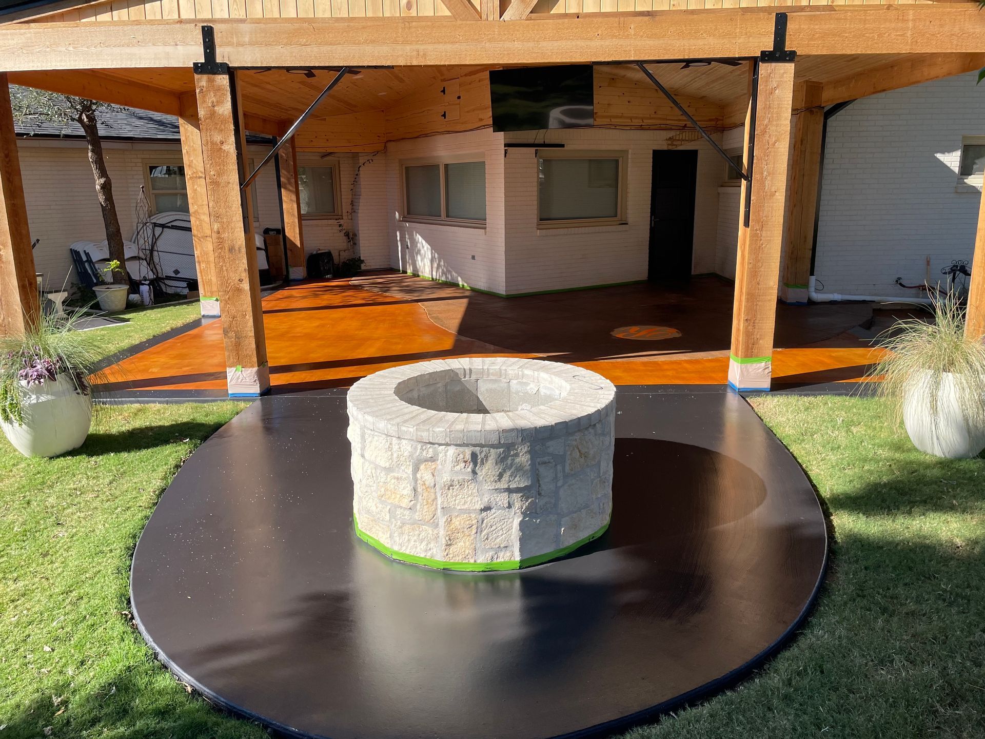 Outdoor patio with a fire pit, stained concrete flooring, and wooden beams.