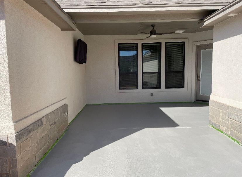 Covered patio with gray floor, windows, door, and a ceiling fan.