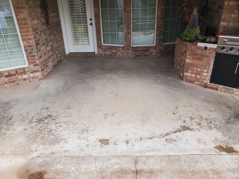 Concrete patio with brick walls, a door, and a grill.