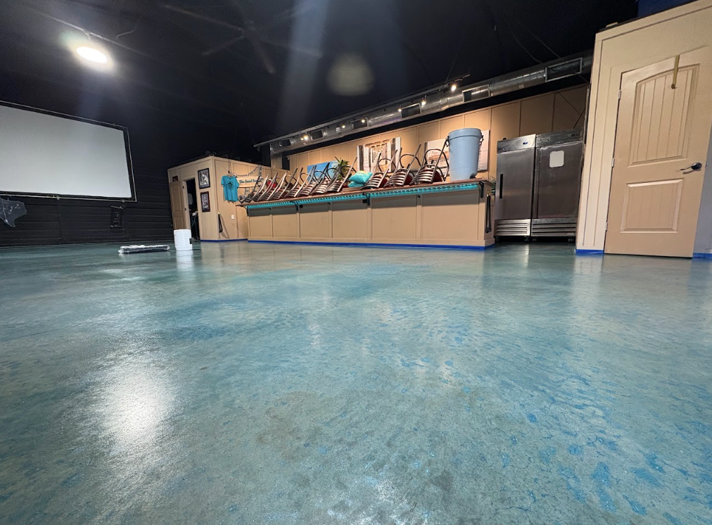 Empty studio with blue floor, stage lights, a long counter, and a projection screen on the left