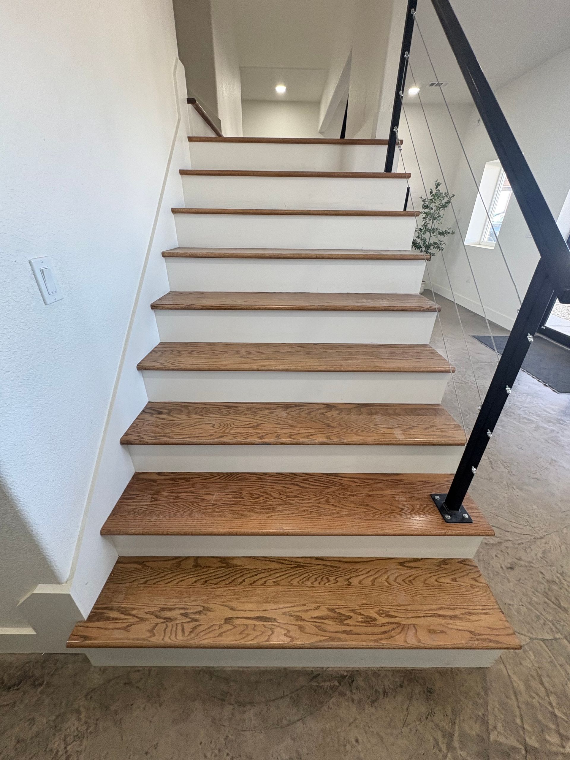 Wooden staircase with white risers and black railing.