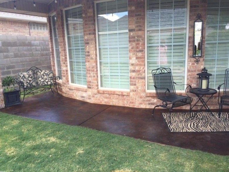 Brown stained concrete porch with brick trim and columns, reflecting sunlight, setting outdoors.