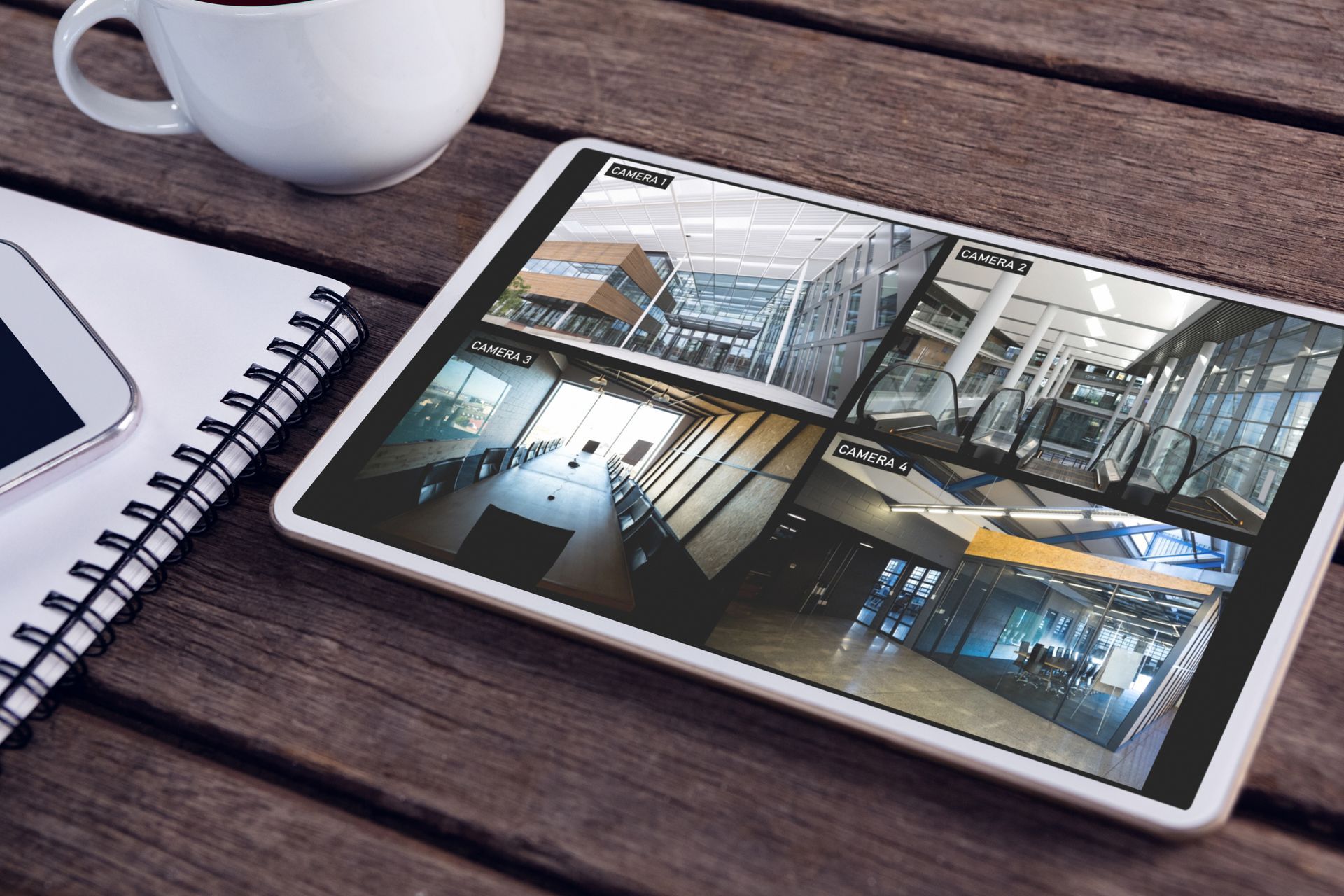 Tablet displaying a multi-camera security monitoring system on a desk.