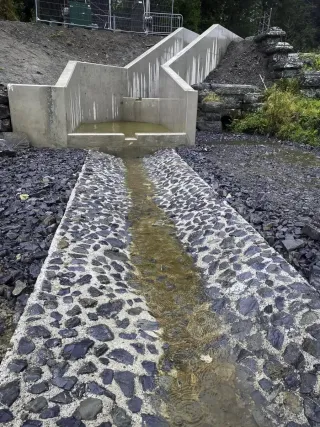 Water flows down a series of concrete steps into a cobbled channel.