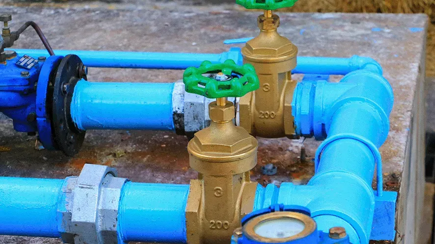 Blue water pipes with two brass valves and a gauge.