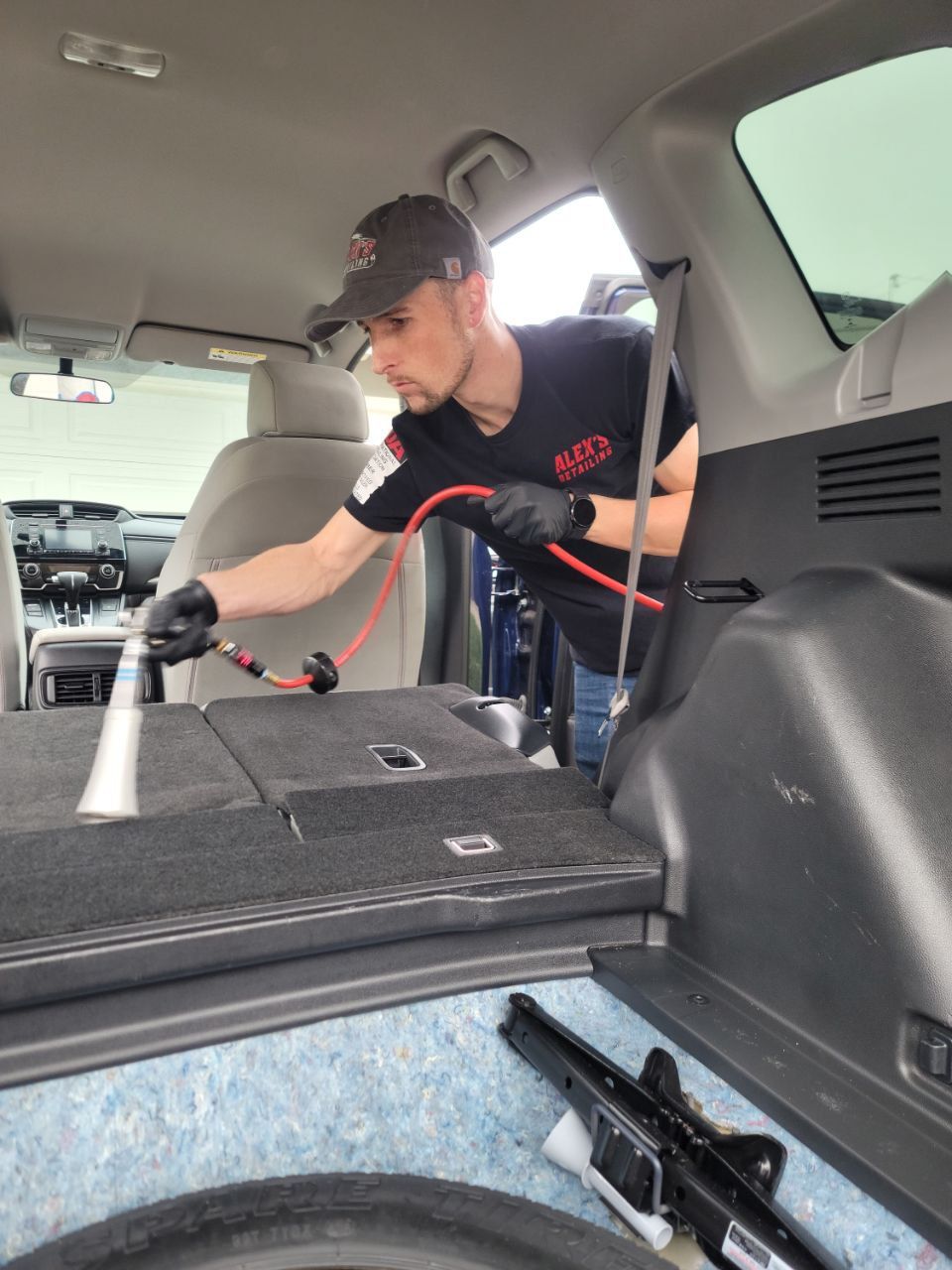 A man is cleaning the back seat of a car