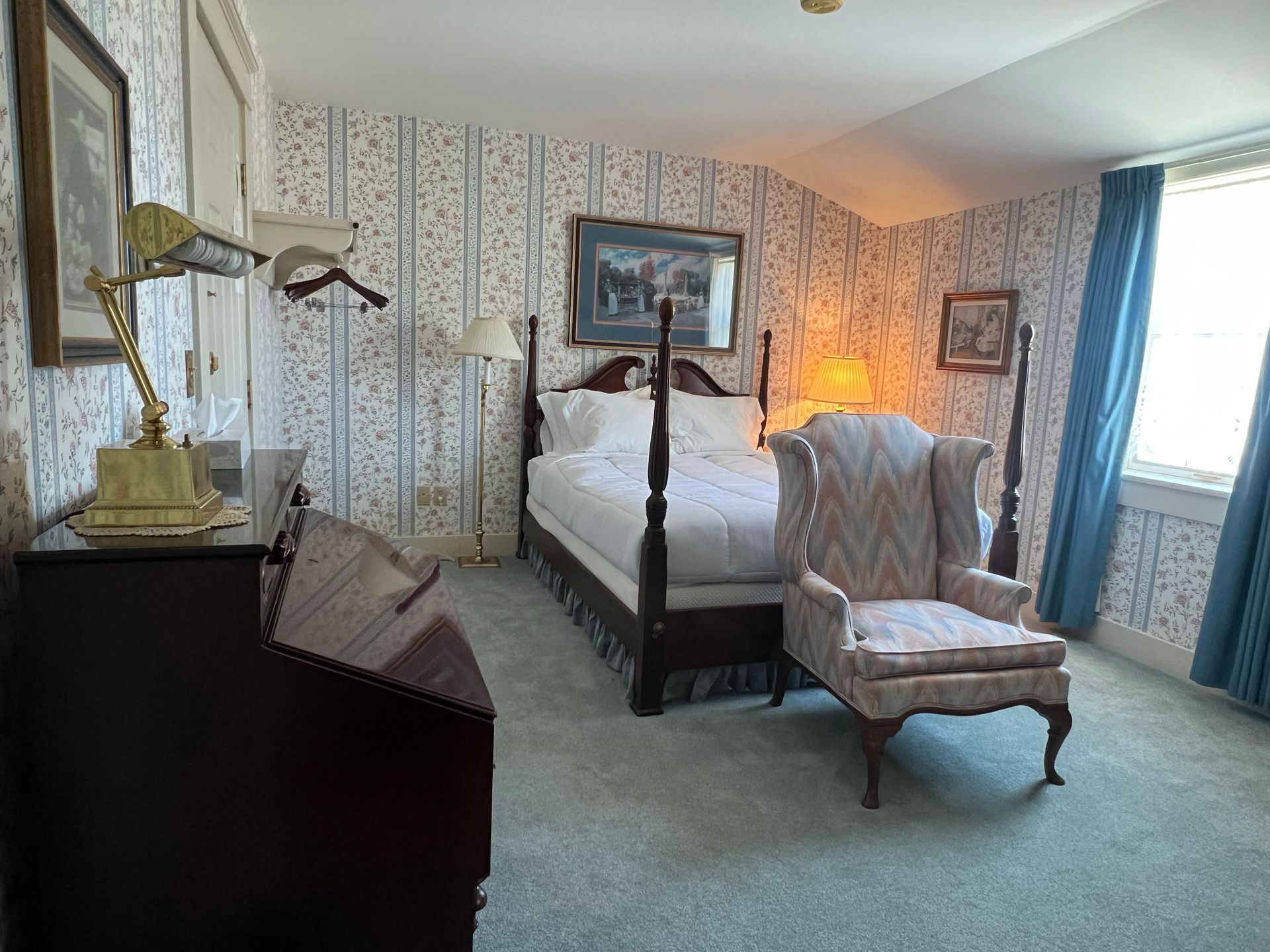 Volendam Kamer Room 16 featuring a queen bed, floral wallpaper, bedside table, and upholstered armchair at the Strattown Inn.