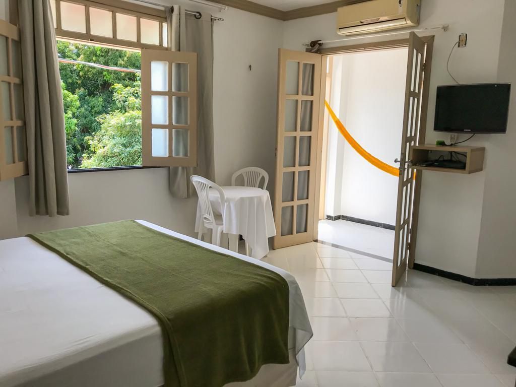 Um quarto de hotel com uma cama, mesa, cadeiras e televisão.