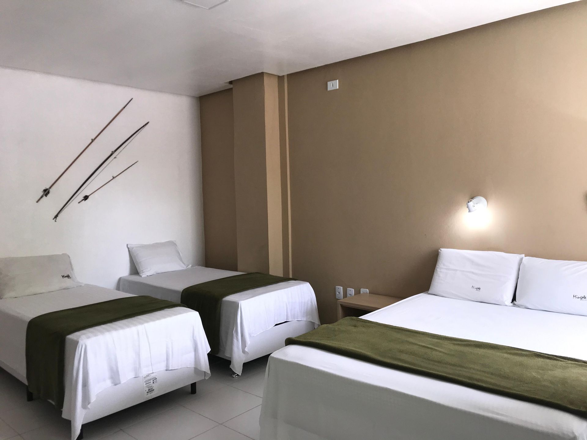 Um quarto de hotel com três camas e duas espadas na parede