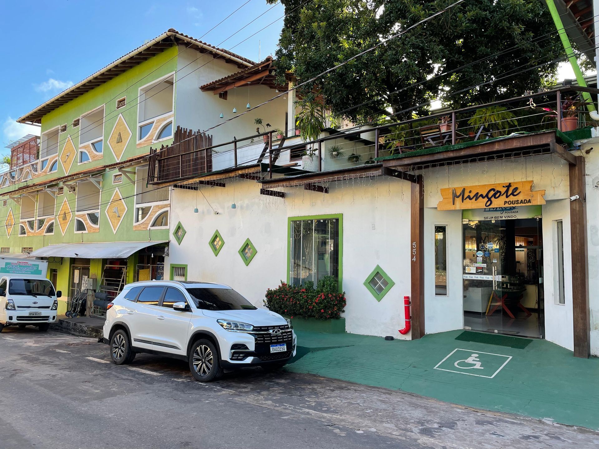 Um utilitário esportivo branco está estacionado em frente a um prédio.