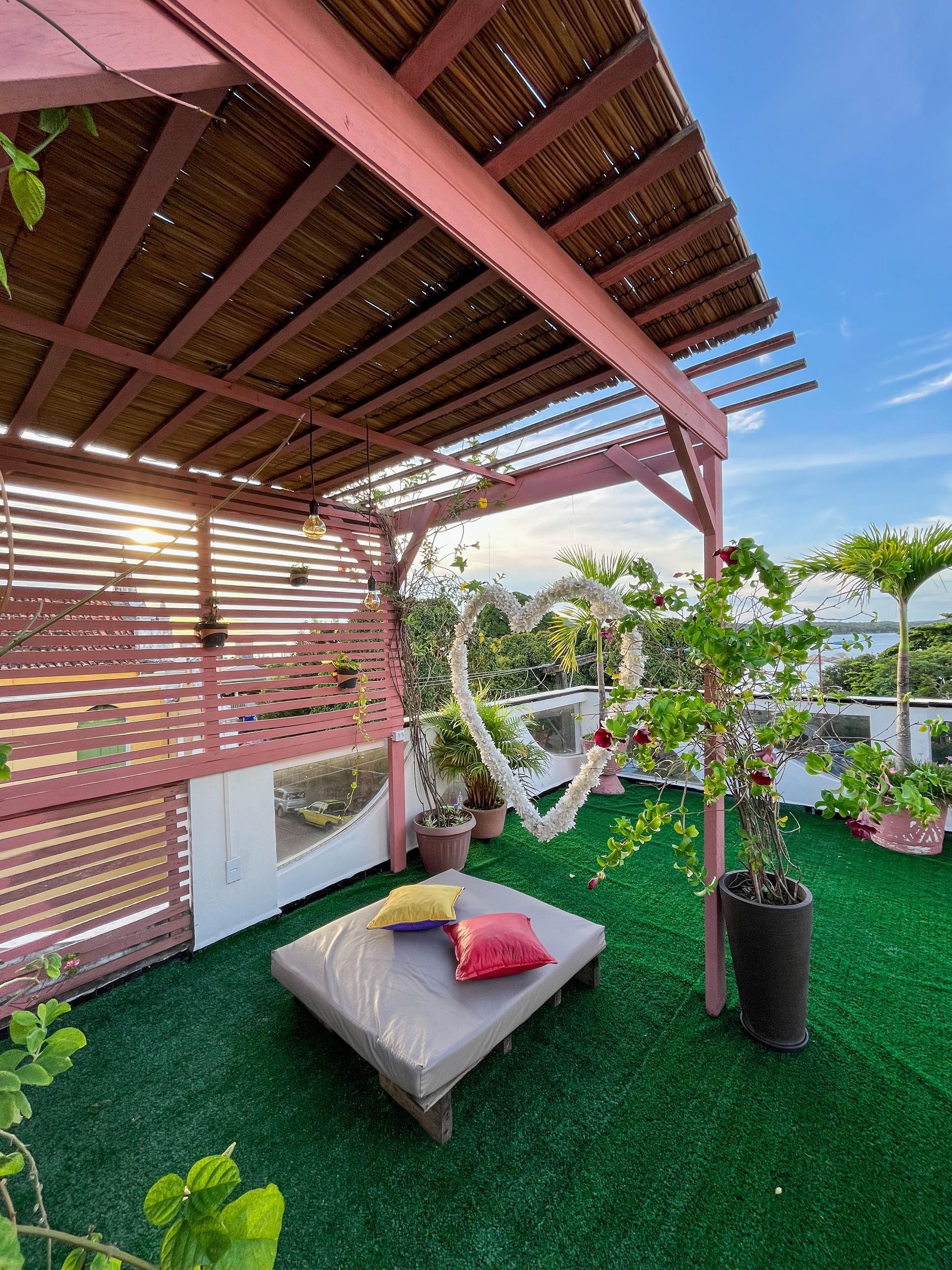 Um pátio com uma rede e uma mesa sob uma pérgola.