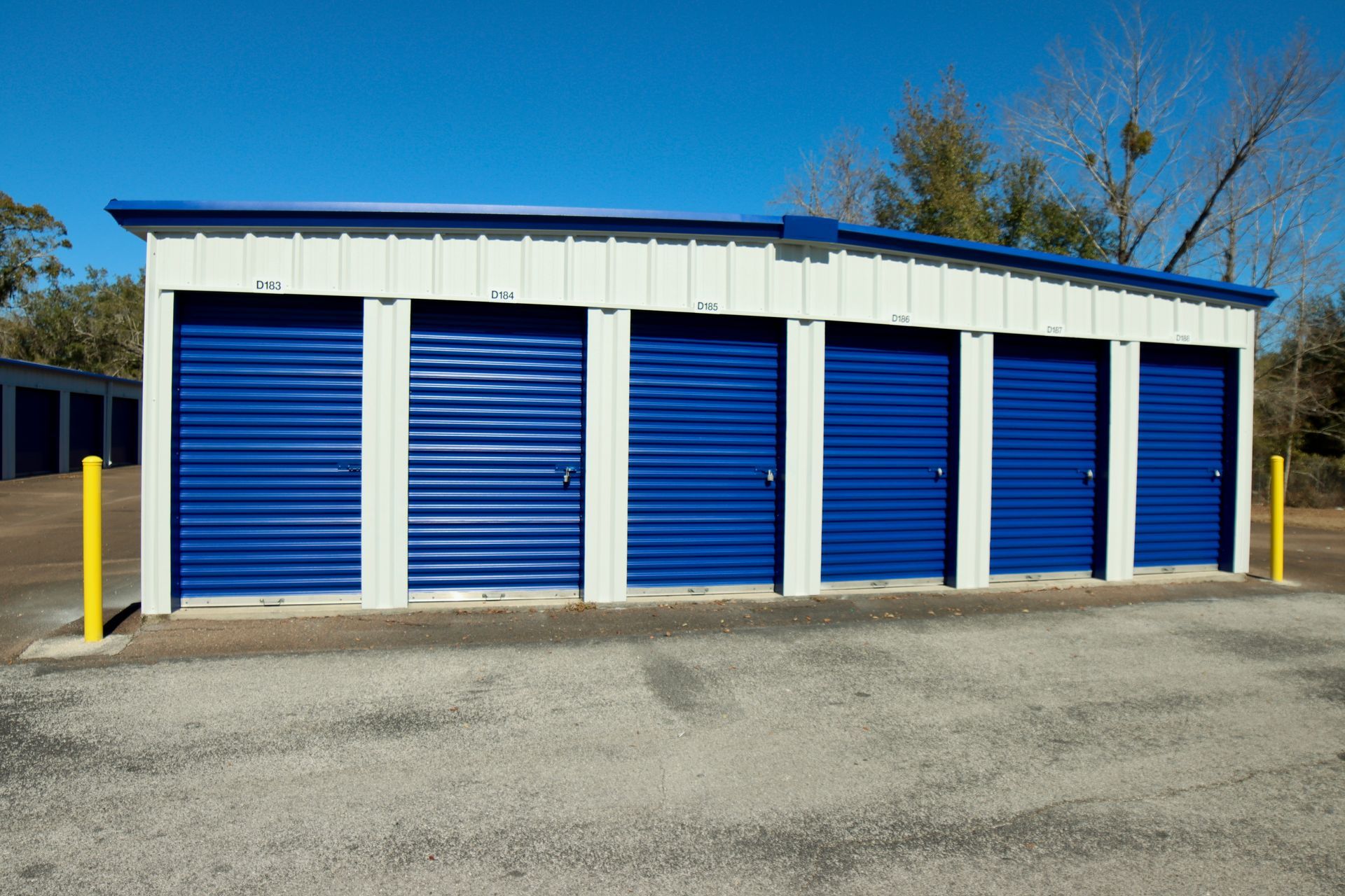 Storage units with blue doors and a white and blue roof under a clear, blue sky.