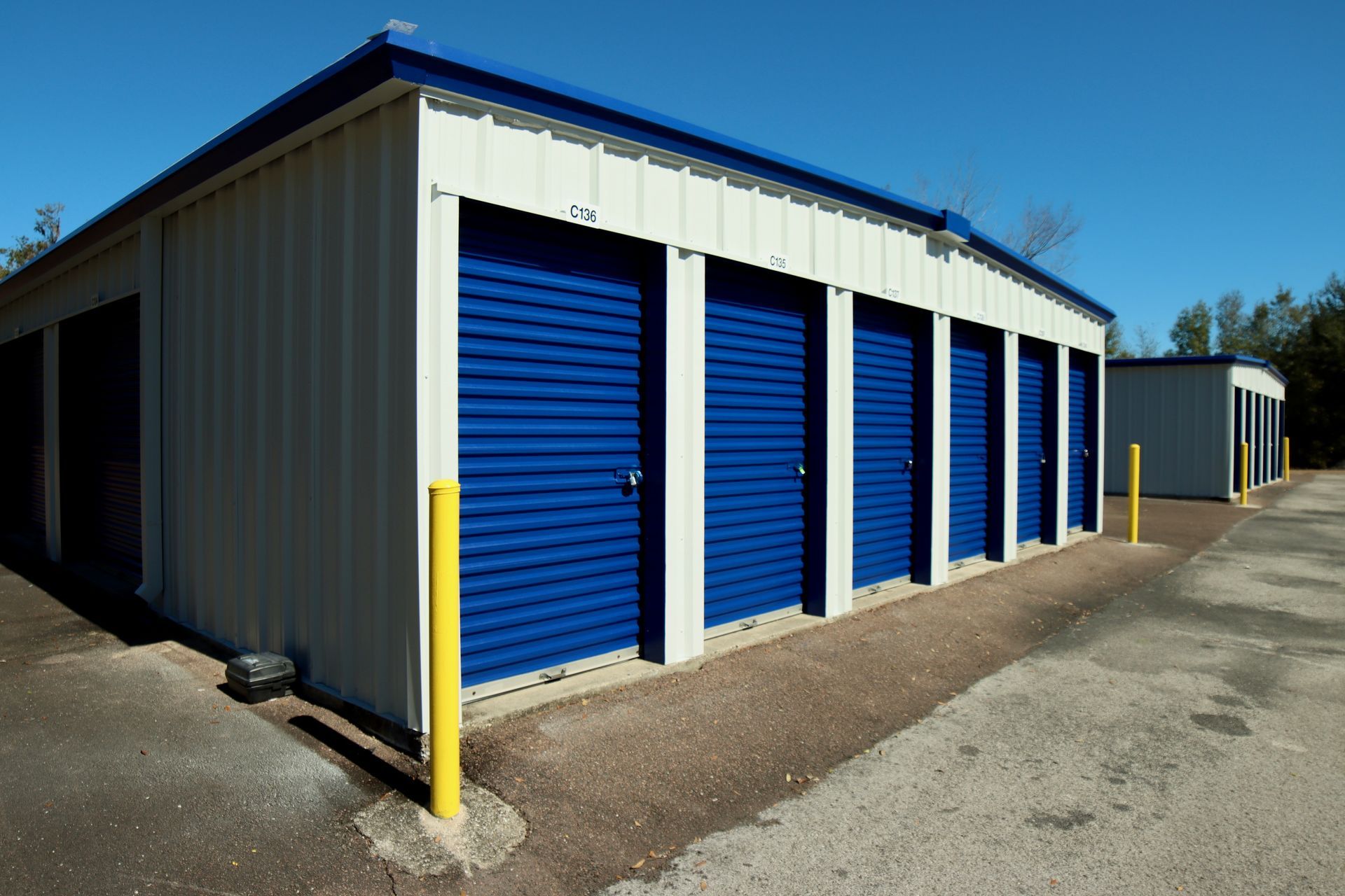 Exterior view of a self-storage facility with blue doors and a white building under a clear sky.