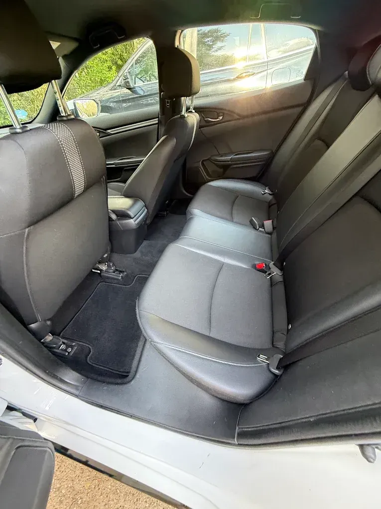Rear car seat interior with black upholstery and sunlight through the side window