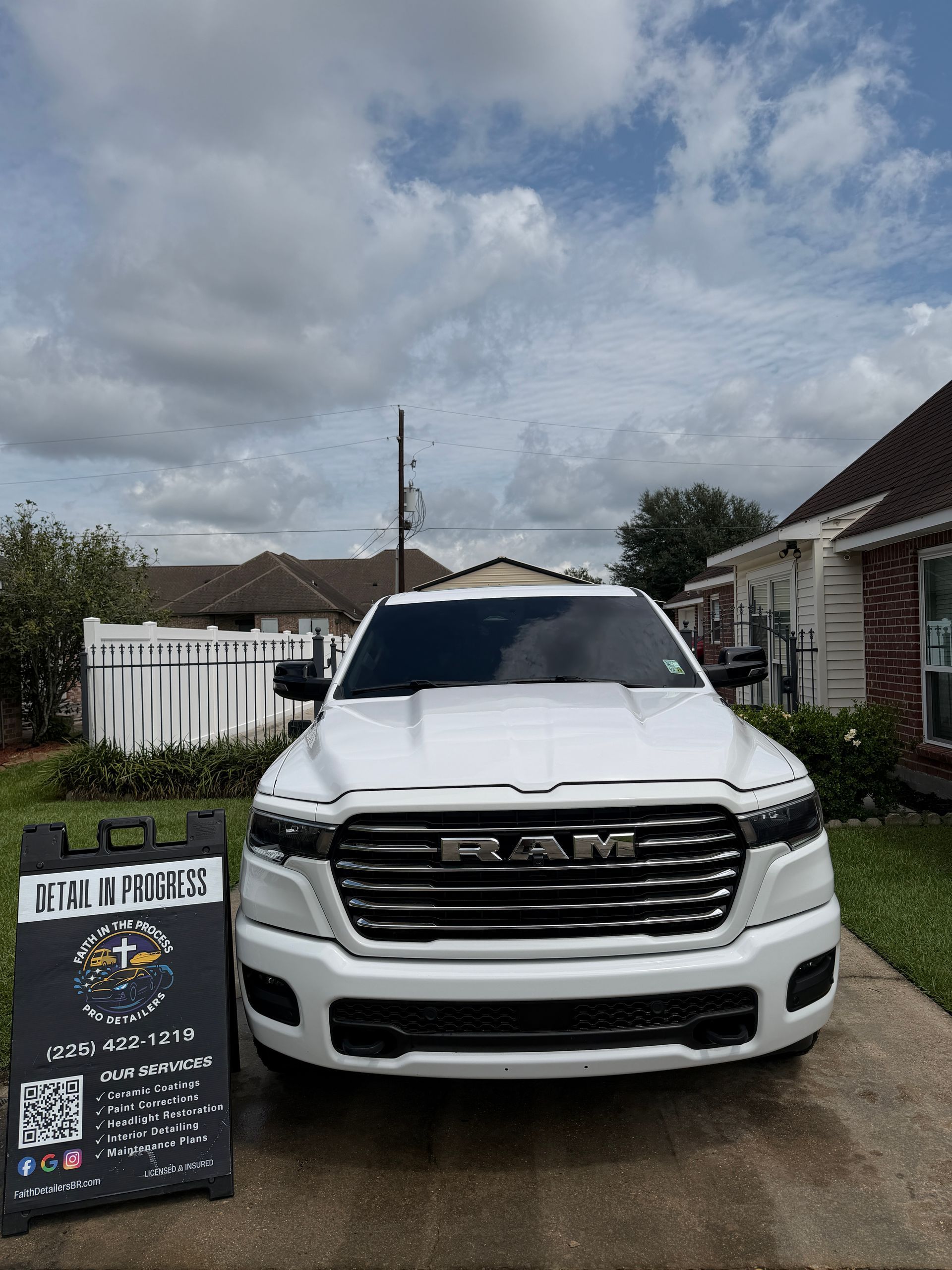 White Lexus SUV parked in a driveway beside a real estate sign under a cloudy sky