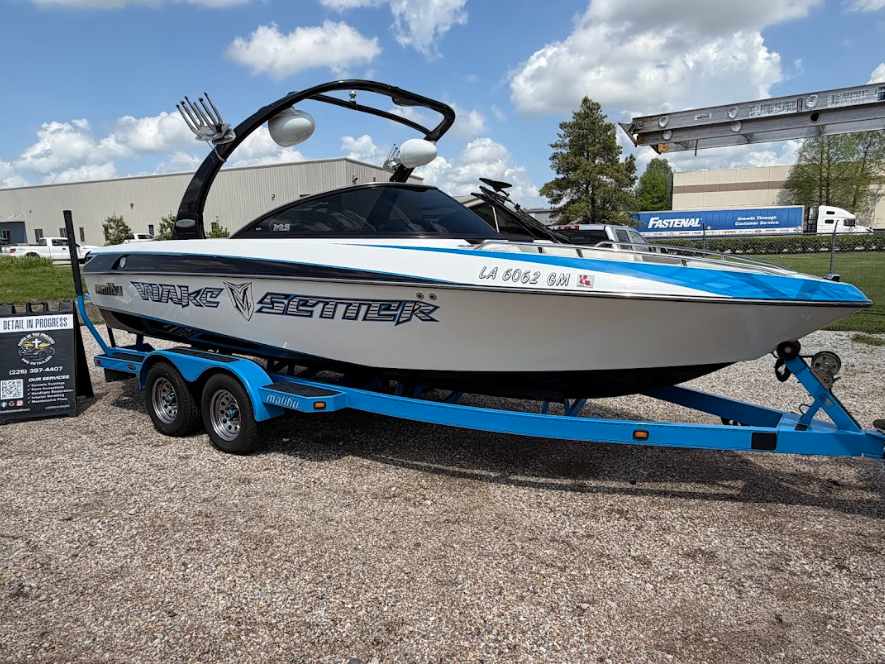 Blue-and-white speedboat on a trailer at an outdoor lot under cloudy sky