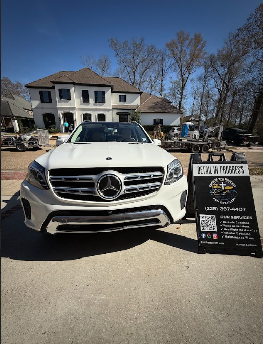 White Mercedes SUV parked outside a house, with a signboard in front under a clear blue sky.