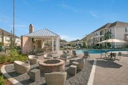 Apartment courtyard with pool, gazebo, and fire pit seating area under a blue sky