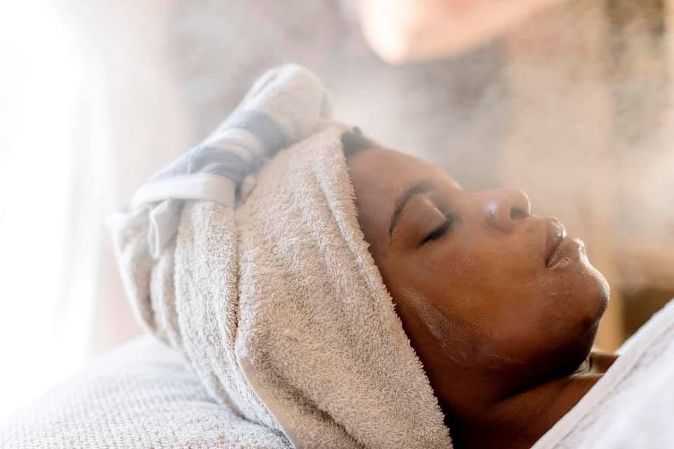 Person with a towel wrapped around their head relaxing during a spa facial treatment