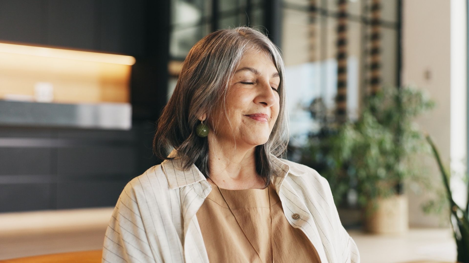 Woman smiling in a bright modern office with plants and warm lighting