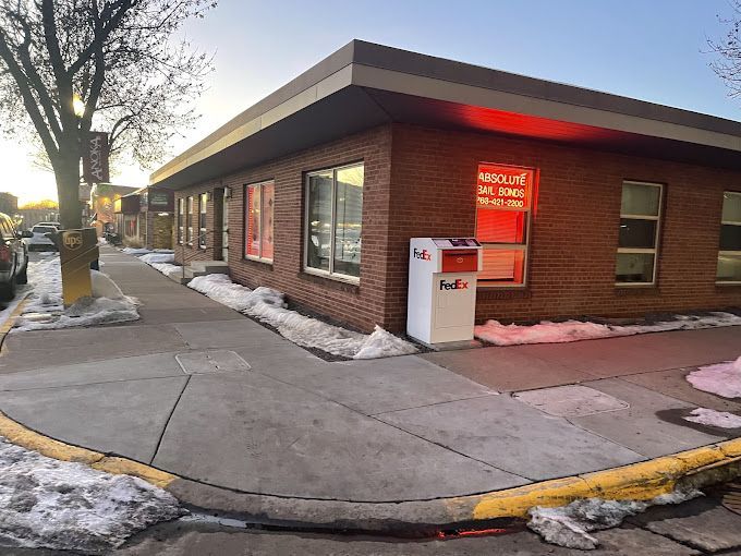 Corner brick building with a FedEx drop box, sidewalk, and melting snow on a winter day.