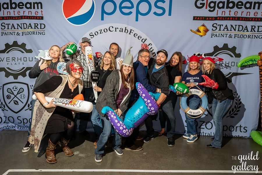 A group of people are posing for a picture in front of a pepsi sign.