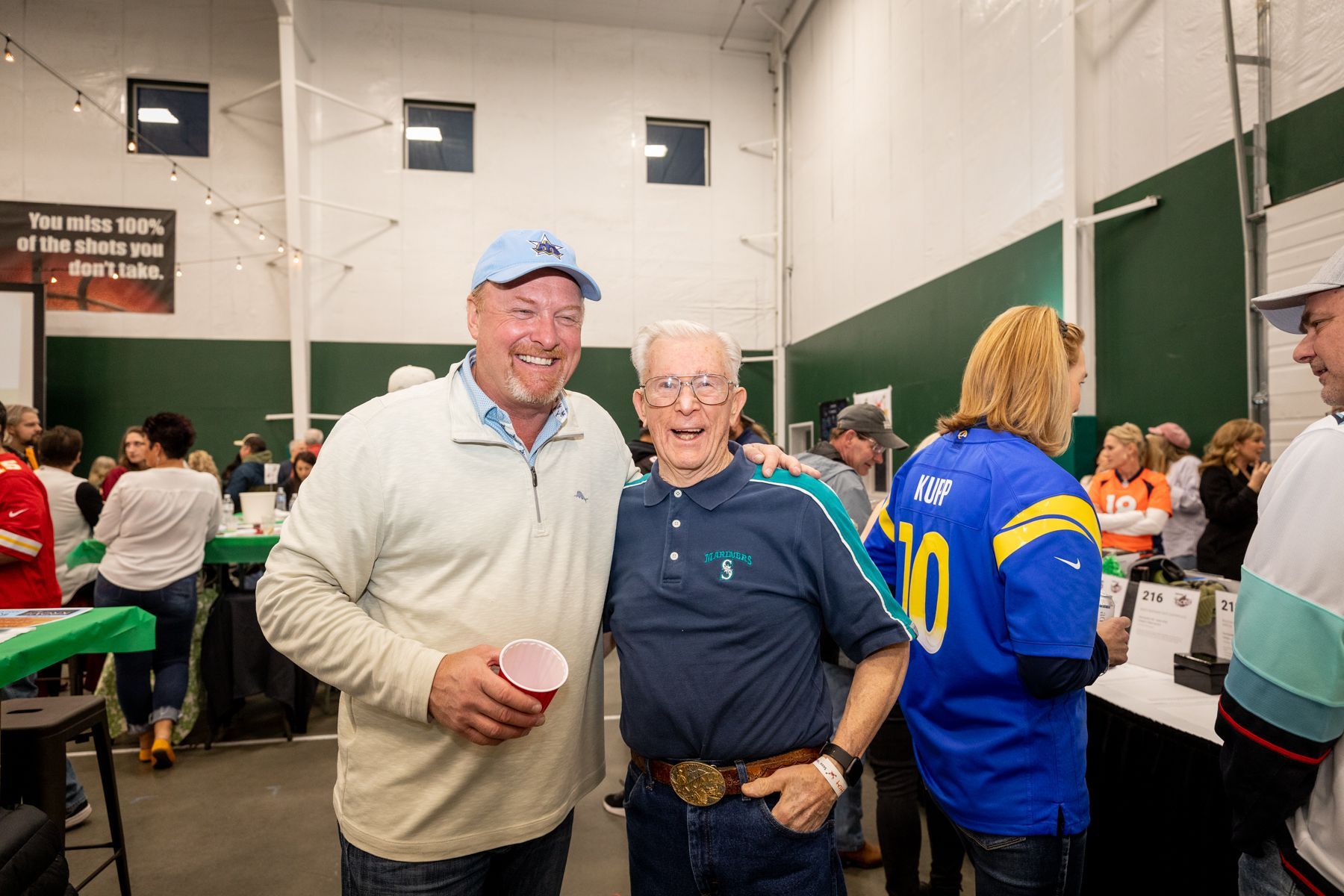 Two men are posing for a picture in a crowded room.