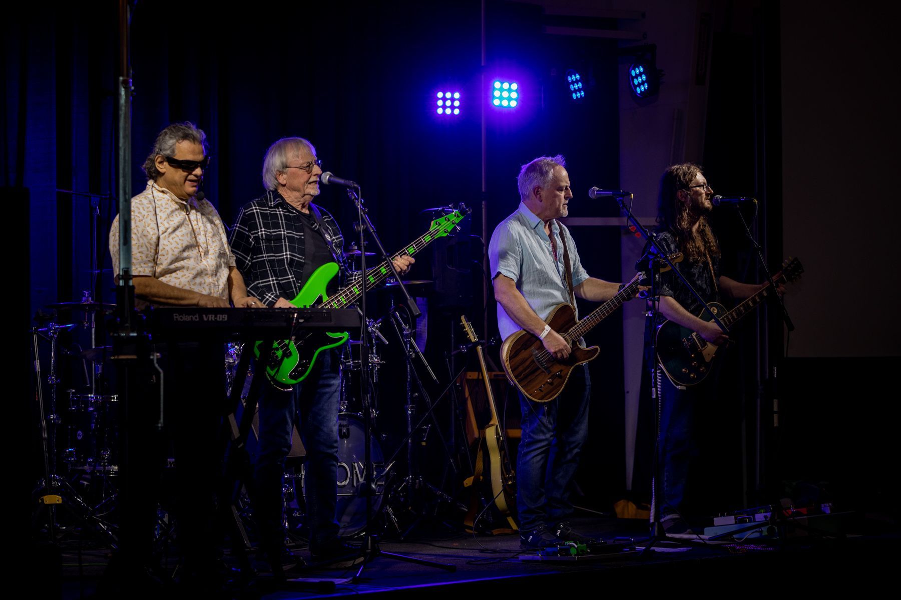 A group of men are standing on a stage playing guitars and singing into microphones.