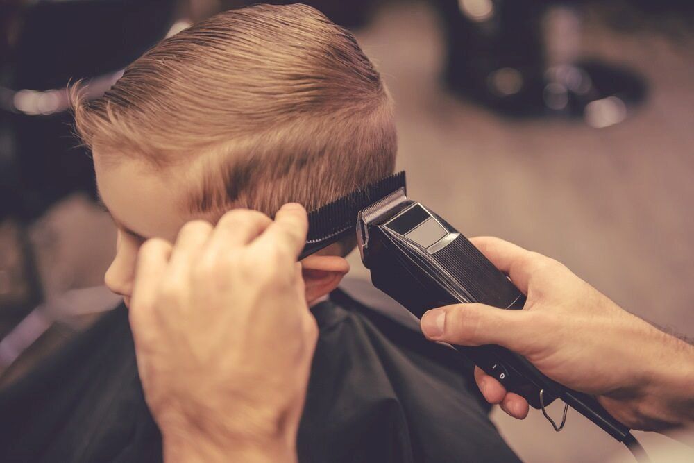 Barber Trimming a Young Boy's Hair With Electric Clippers — Bermann Barbershop in Casey, ACT