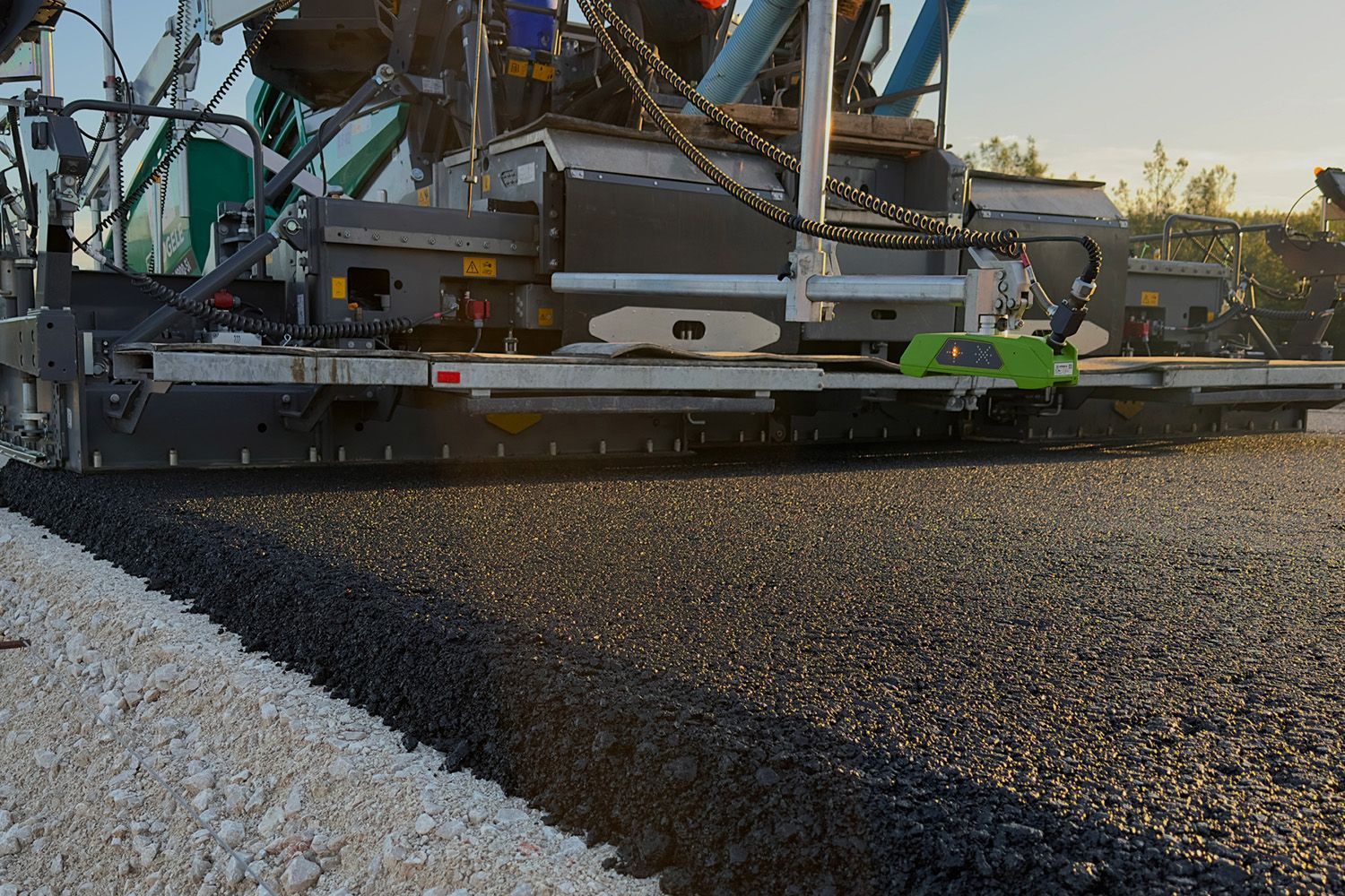 A machine is laying gravel on a road.