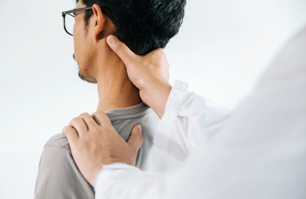 A Man Is Getting His Neck Examined By A Doctor — Grays Chiropractic Centre In Beaconsfield, QLD