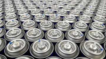 A bunch of cans of spray paint are lined up on a table.
