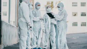 A group of people in protective suits are standing next to each other.