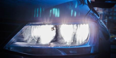 A close up of a car headlight in the dark.