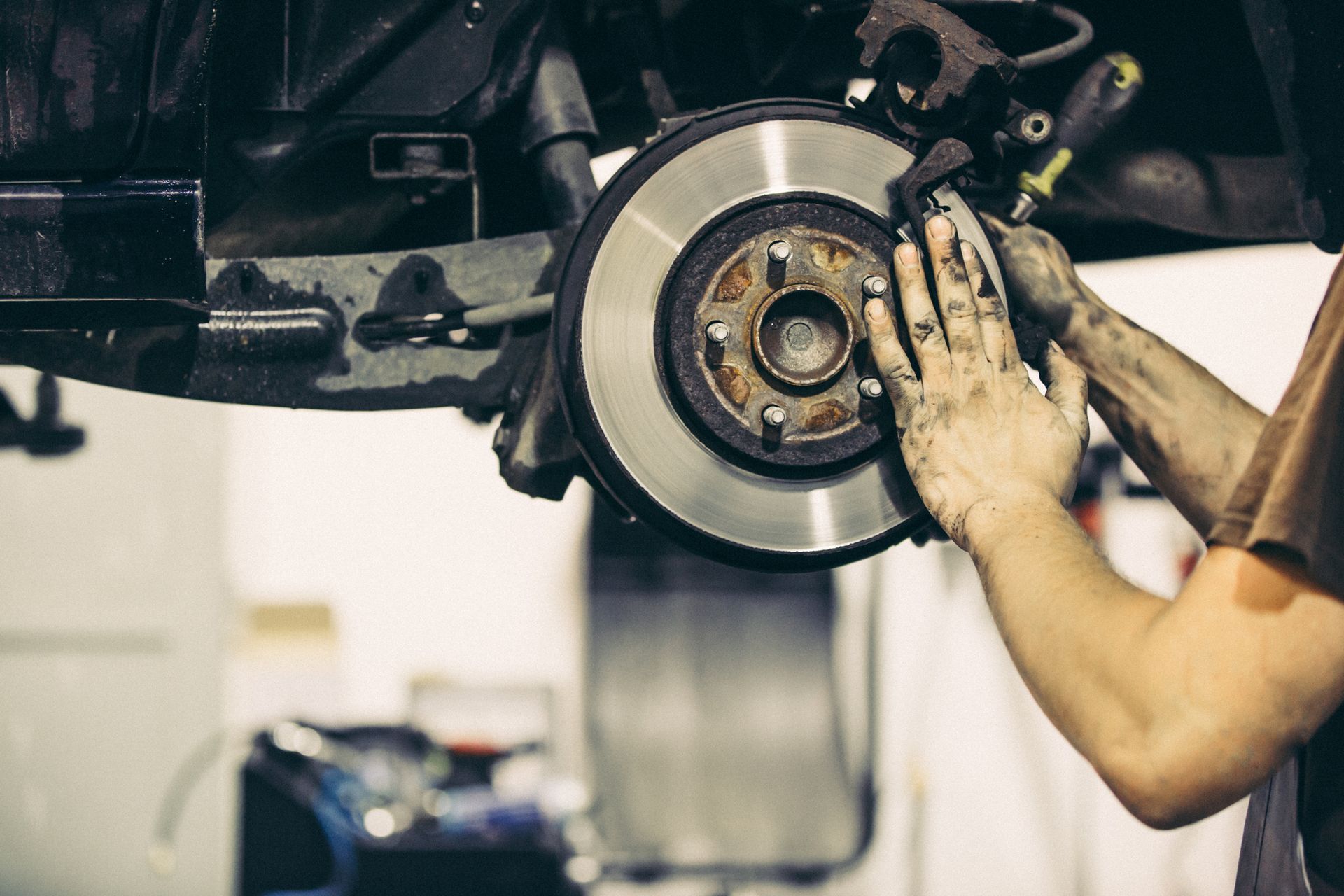 A man is fixing a brake disc on a car in a garage.