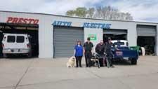 A group of people standing in front of a garage with a dog.
