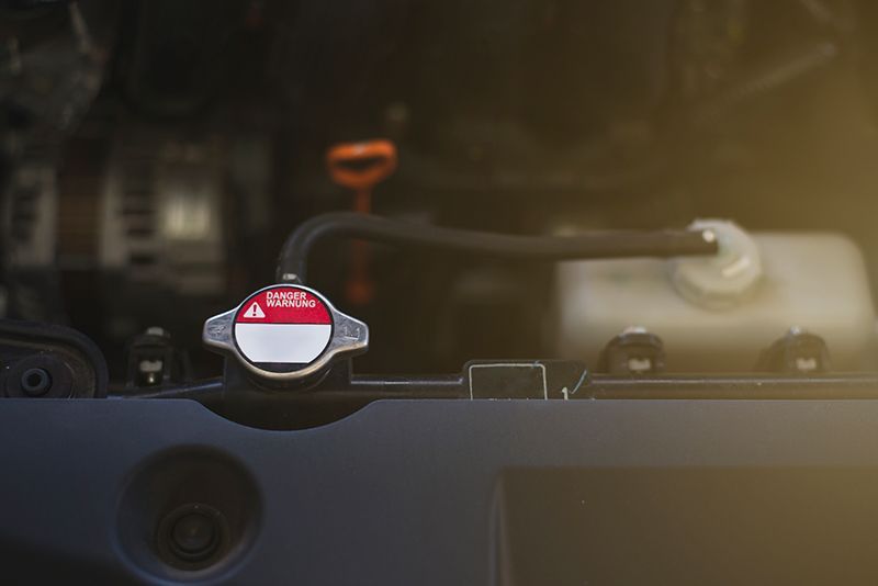 A close up of a radiator cap on the hood of a car.