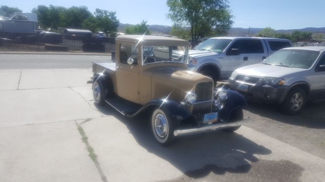 An old truck is parked in a parking lot next to other cars.