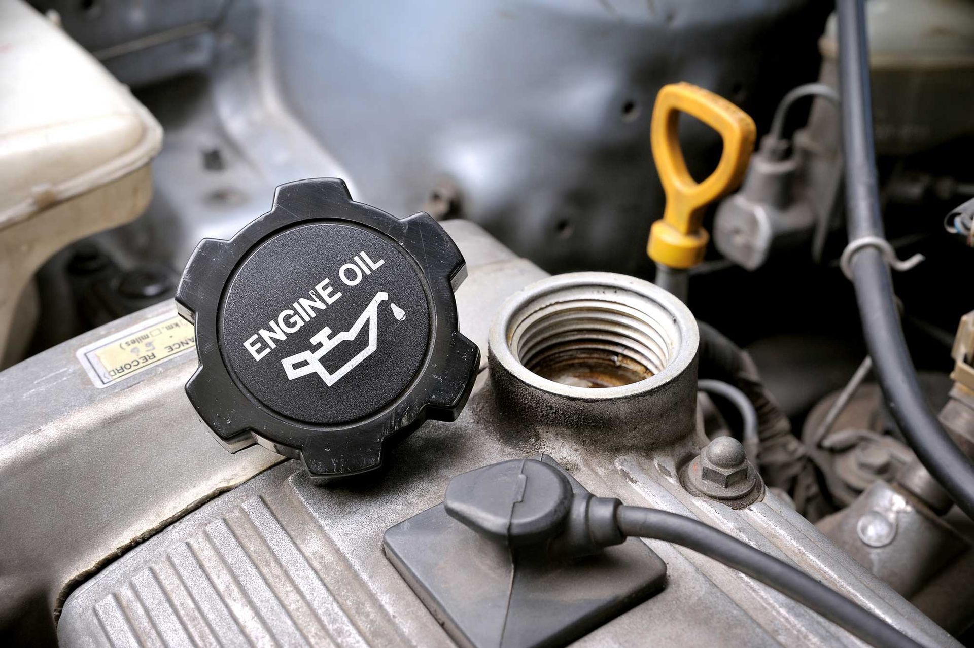 A close up of an engine oil cap on a car engine.