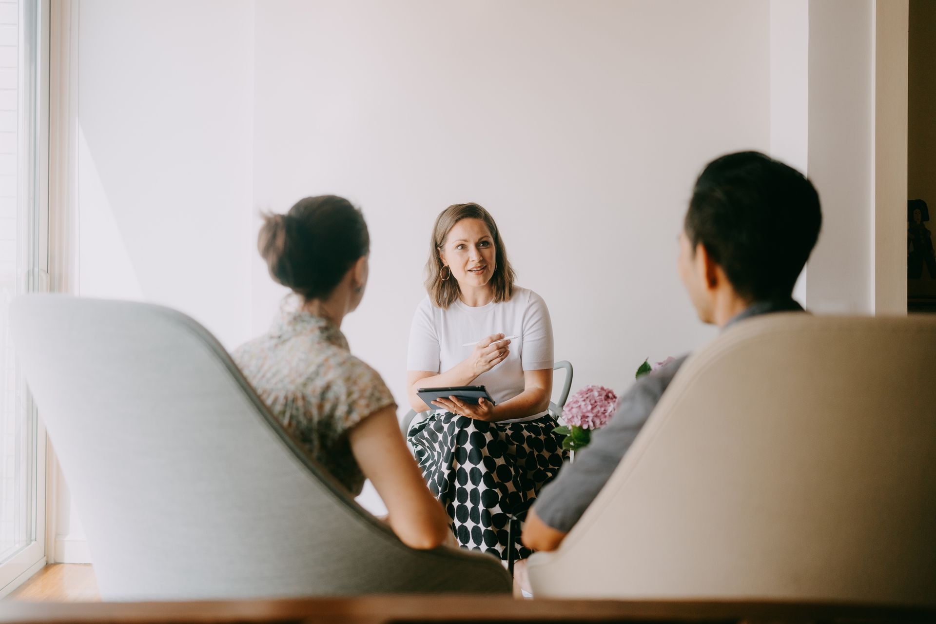 A female therapist guiding a couple through marriage counselling.