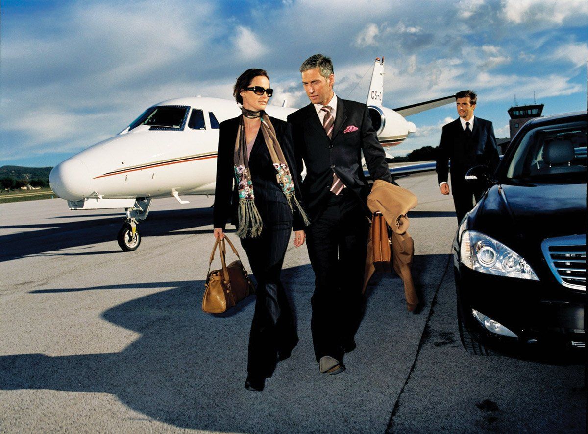 professional couple in front of lear jet getting into limo