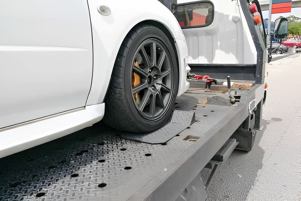 A White Car Is Being Towed By A Tow Truck — Cam Duffy Autos In Atherton, QLD